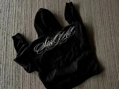 Black cropped hooded top with white script across the chest