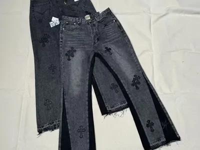 Two pairs of dark washed jeans with cross patches laid flat